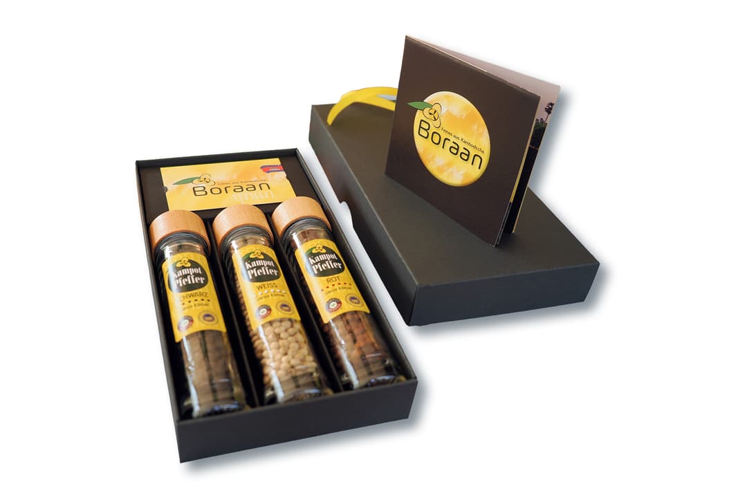 Geöffnete Geschenkbox mit drei Pfeffergläsern neben einer aufgeklappten Boraan-Markenkarte