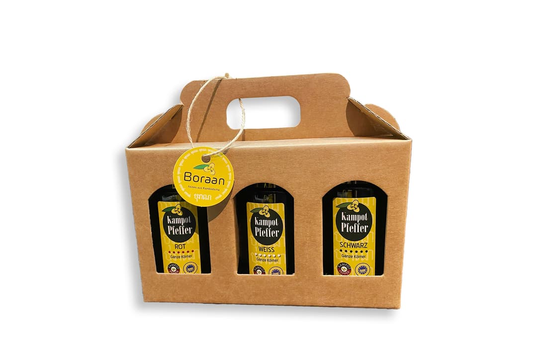 Open kraft-paper gift carrier holding three pepper bottles, tied with a Boraan tag