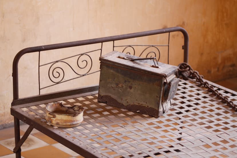 Rusted metal bed frame and ammunition box, a preserved exhibit at a Khmer Rouge historical site