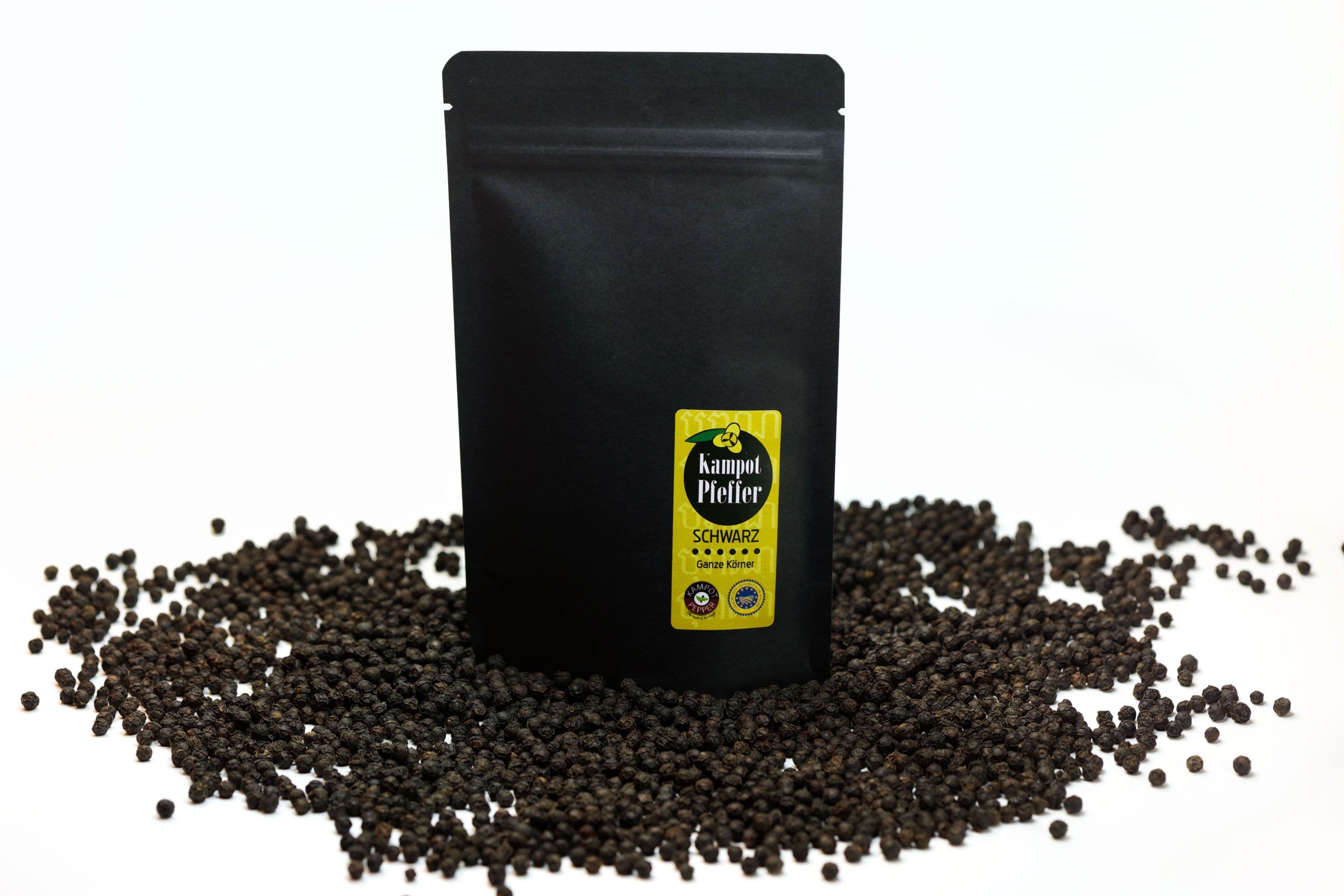 Black stand-up pouch of Kampot black pepper on scattered black peppercorns